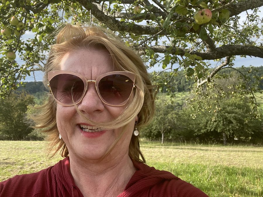 Anne Knapp lachend unter einem Apfelbaum auf einer Streuobstwiese im Nordschwarzwald